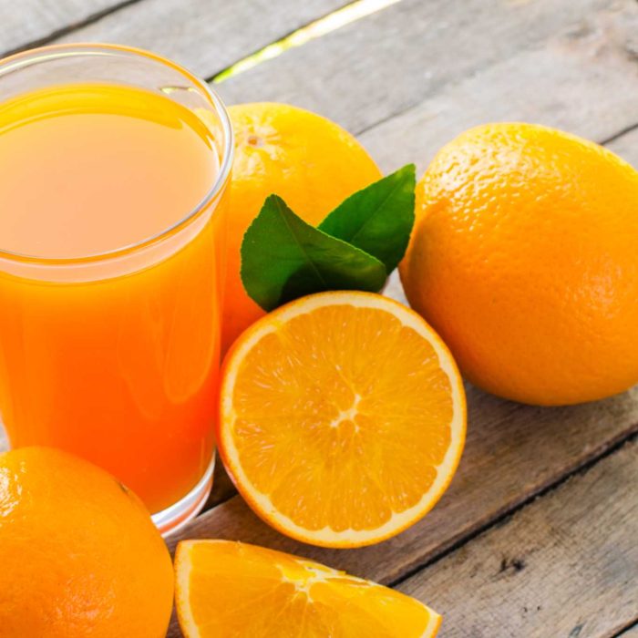 Orange juice in glass , fresh fruits on wooden background